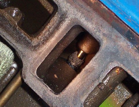 1980 Ford Bronco - This image shows a close-up of an engine valve and its surrounding components, covered in oil and grime.