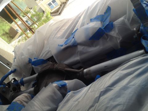 2013 Ford Mustang - A vehicle is covered in plastic sheeting and blue tape, obscuring most of its details.