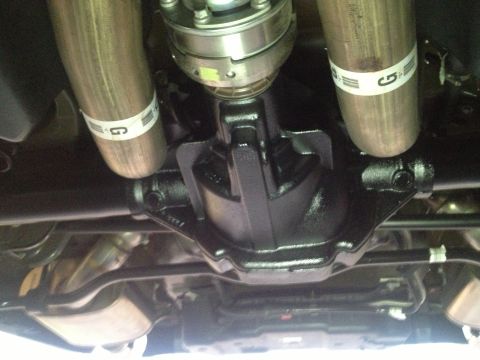 2013 Ford Mustang - Undercarriage view of a rear differential and dual exhaust pipes, each with a white band containing a 'G' logo.