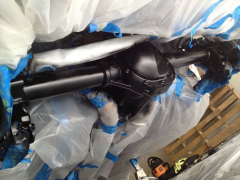 2013 Ford Mustang - A rear axle assembly is covered in plastic and tape, suggesting it is being prepped for painting or protection.