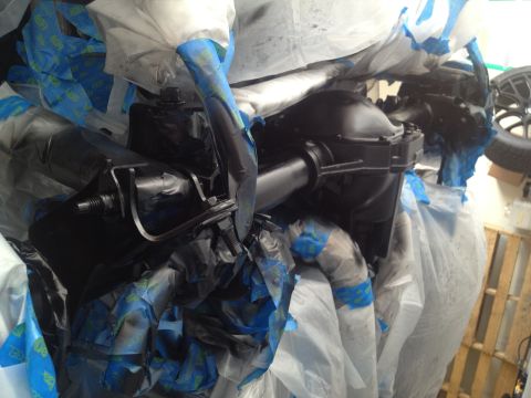2013 Ford Mustang - A rear axle assembly is covered in protective plastic and blue painter's tape, likely before being painted or worked on.