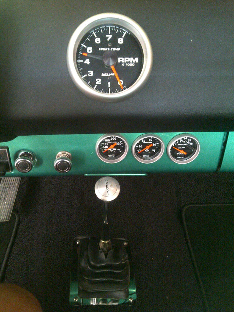 Dashboard with tachometer, oil pressure, and voltage gauges. Floor shifter is visible