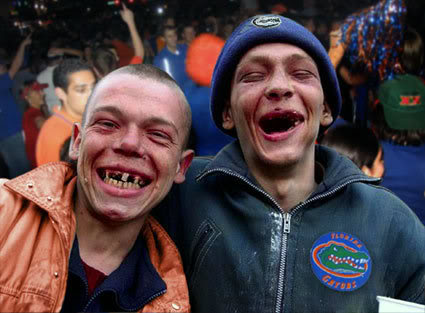1986 Ford Bronco - Two men with missing teeth laugh heartily in a crowded outdoor setting, one wearing an orange jacket and the other a blue beanie and jacket.