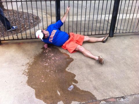 1986 Ford Bronco - A man is seen lying on the ground next to a metal fence, with a puddle of liquid nearby.