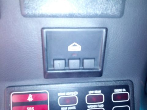 1989 BMW 3 Series - Close-up of car interior controls, including a garage door opener button and indicator lights for vehicle functions.