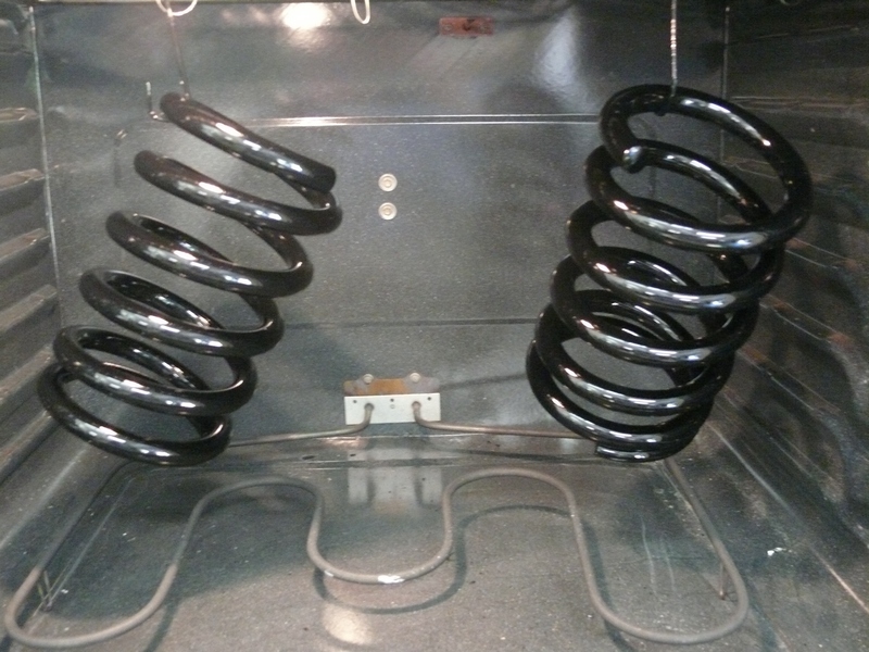 Two black suspension springs hanging inside an oven