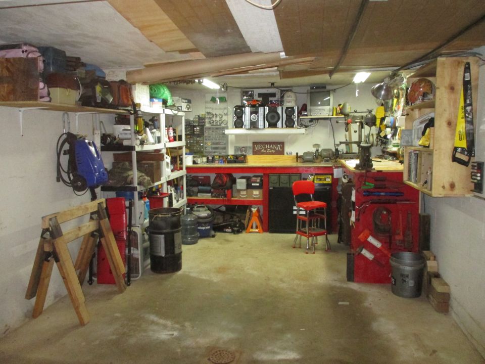 Garage interior with red workbench, tools, shelves, and a red stool