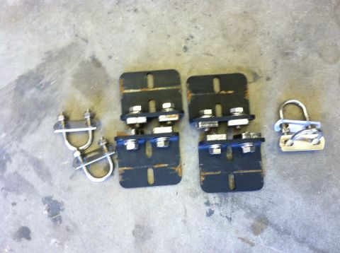 2003 Toyota 4Runner - Various metal hardware, including brackets, U-bolts, and a padlock, are laid out on a concrete floor.