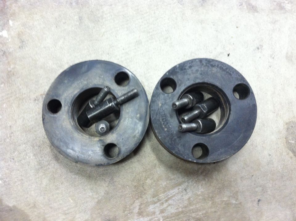 Two black automotive parts with bolts