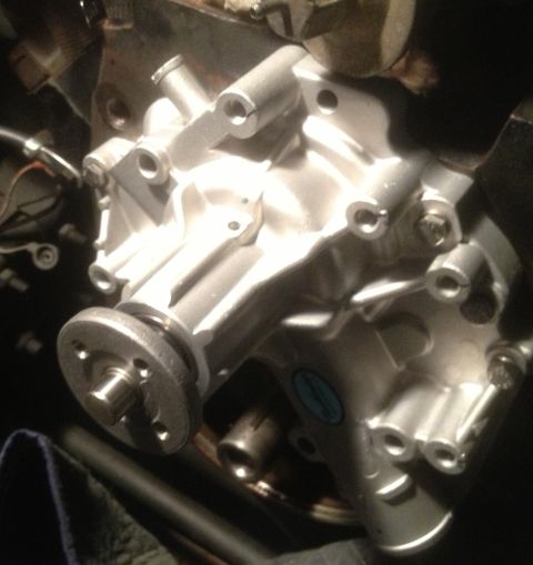 1978 Ford Bronco - Close-up of a vehicle's water pump assembly, showing mechanical components and a blue circular sticker.