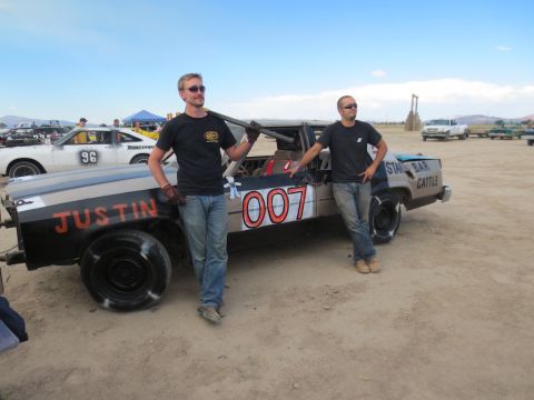 1989 Ford Bronco - Two men pose with a heavily modified car, possibly for a demolition derby event.