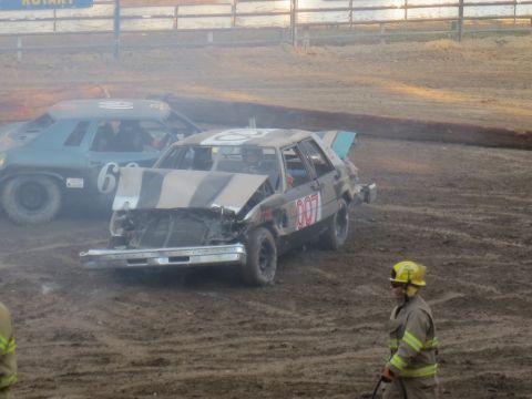 1989 Ford Bronco - Cars are lined up in a dirt arena, ready for a demolition derby event. One car has the number 007 displayed.