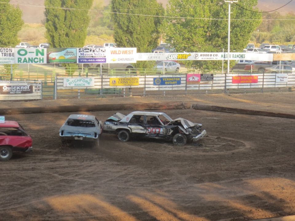 Demolition derby cars on dirt track, one heavily damaged sedan with "VALLEY 161" visible