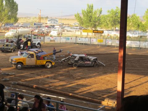 1989 Ford Bronco - A severely damaged car is towed away from a demolition derby arena.