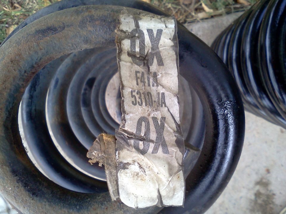 Two black coil springs, one with a torn label showing part numbers F41A 5310-JA