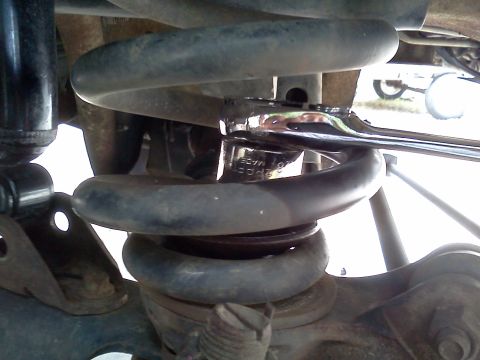 1995 Ford Bronco - Wrench being used on a vehicle's suspension coil spring.