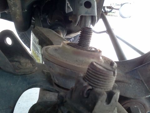 1995 Ford Bronco - Detail of a vehicle's front suspension assembly, focusing on the coil spring mount and shock absorber bolt.