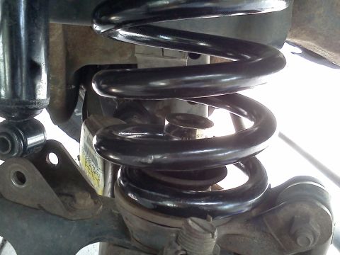 1995 Ford Bronco - Close-up view of a vehicle's suspension system, focusing on the coil spring and shock absorber.
