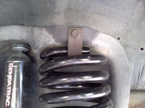 1995 Ford Bronco - Close-up of a front coil spring and a Sensatrack shock absorber, likely from a vehicle's suspension system.