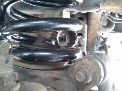 1995 Ford Bronco - Socket wrench is positioned inside a vehicle's suspension coil during maintenance.