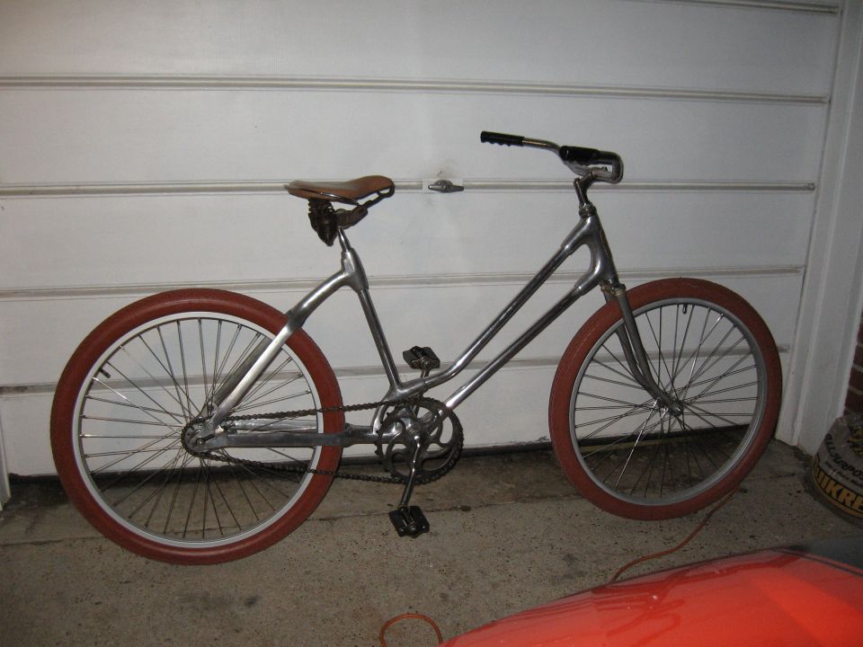 Silver bicycle with brown leather seat and red tires, side view