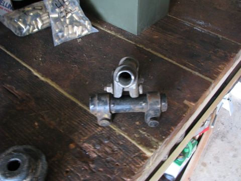 2005 Ford Excursion - A metal automotive part rests on a rustic wooden surface next to bags of ammunition casings.