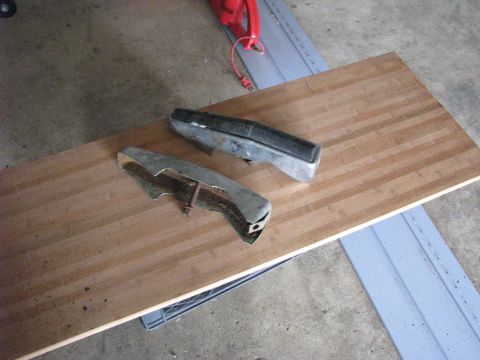 2005 Ford Excursion - Two chrome bumper guards are laid out on a wooden surface, with a red tool in the background.