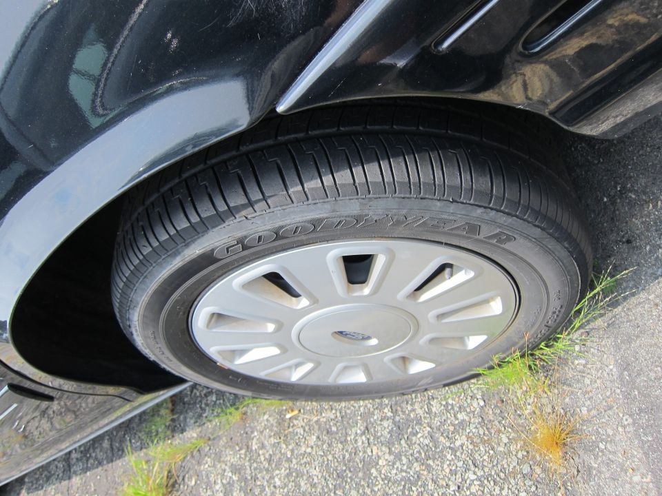 Close-up of a 2001 Ford Crown Victoria's front wheel and fender, showing a Goodyear tire and silver hubcap