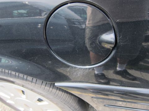 2001 Ford Crown Victoria - Scratches are visible on the black paint around the fuel door of the vehicle.