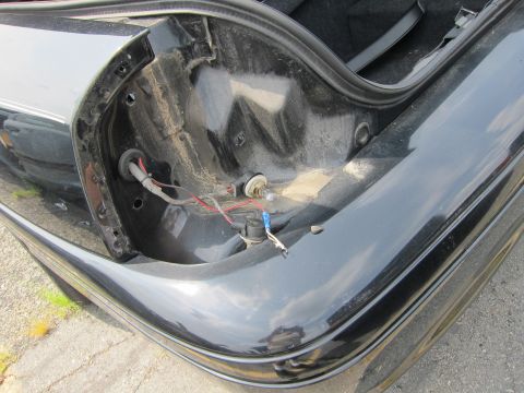 2001 Ford Crown Victoria - The interior of a car trunk reveals exposed wiring and a light bulb socket, with the edge of a taillight visible.