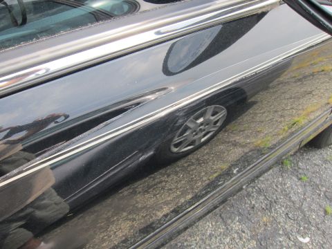 2001 Ford Crown Victoria - Side view of a black 2001 Ford Crown Victoria, showing the door panel, chrome trim, and a reflection of the wheel.