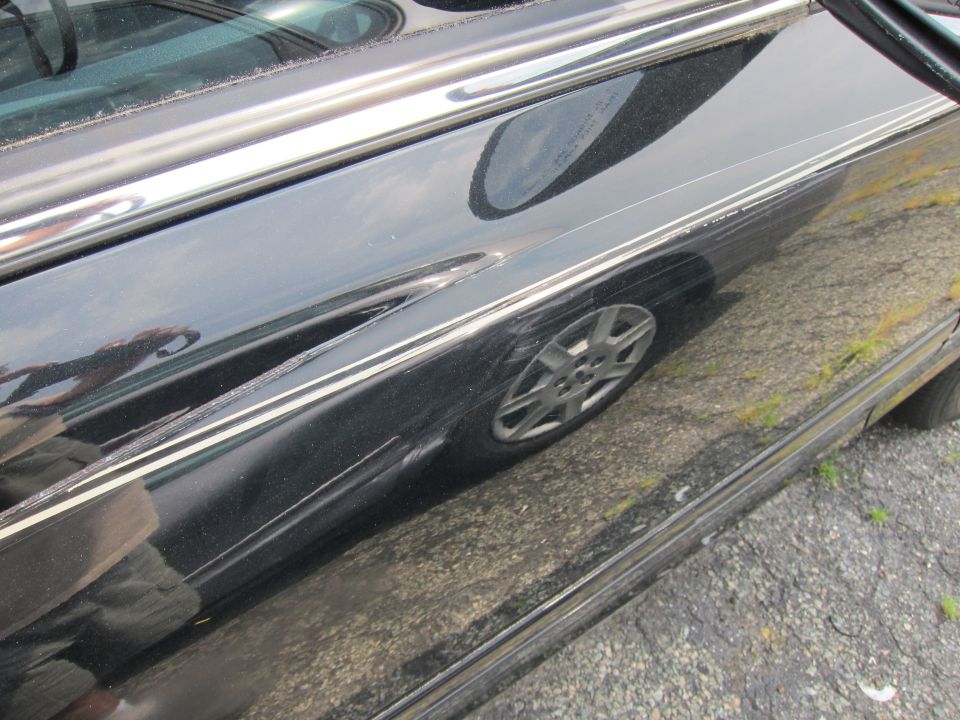 Black 2001 Ford Crown Victoria side panel with chrome trim and wheel reflection