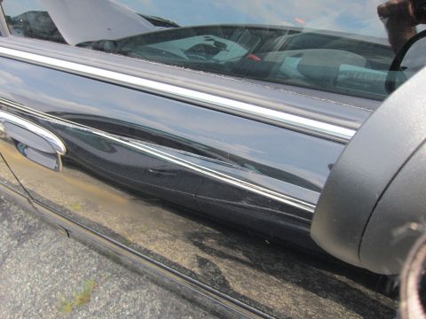 2001 Ford Crown Victoria - Side view of a damaged black car door with visible dents and scratches.