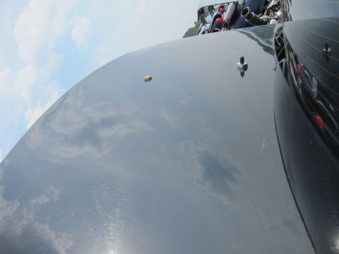2001 Ford Crown Victoria - The glossy black hood of a car reflects the sky and clouds, with a small gold emblem visible.