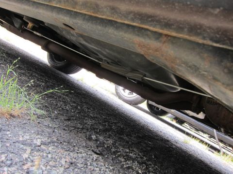 2001 Ford Crown Victoria - A low-angle view of a car's undercarriage reveals rust and a section of the exhaust system.