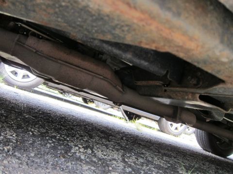 2001 Ford Crown Victoria - A low-angle shot reveals the undercarriage of a vehicle, focusing on the exhaust system and partially visible wheels.