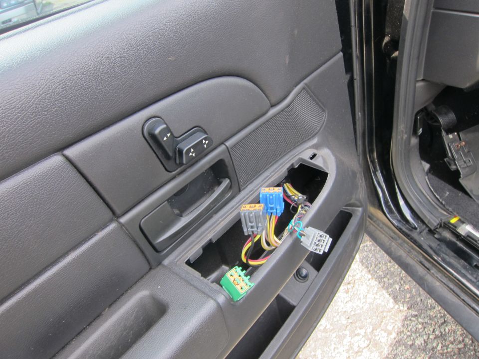 Interior of a car door panel with seat controls and exposed electrical connectors