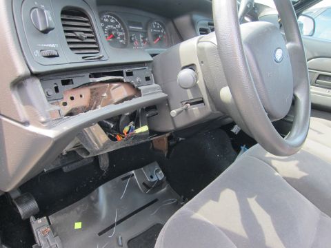 2001 Ford Crown Victoria - Interior view of a damaged 2001 Ford Crown Victoria, revealing exposed wiring and a broken dashboard.