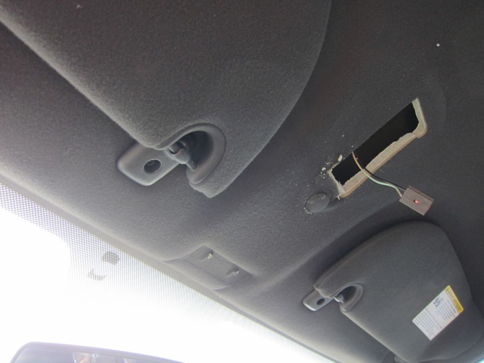 Interior view of car ceiling showing sun visors and a damaged section with exposed wires
