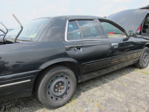 2001 Ford Crown Victoria - Side profile of a black 2001 Ford Crown Victoria with its hood up, parked in an outdoor lot.