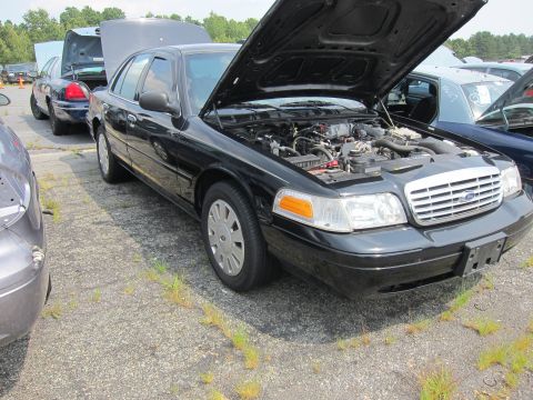 2001 Ford Crown Victoria - A black 2001 Ford Crown Victoria is parked with its hood open, revealing the engine compartment.