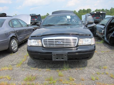2001 Ford Crown Victoria - Junkyard scene with a black 2001 Ford Crown Victoria as the main subject.