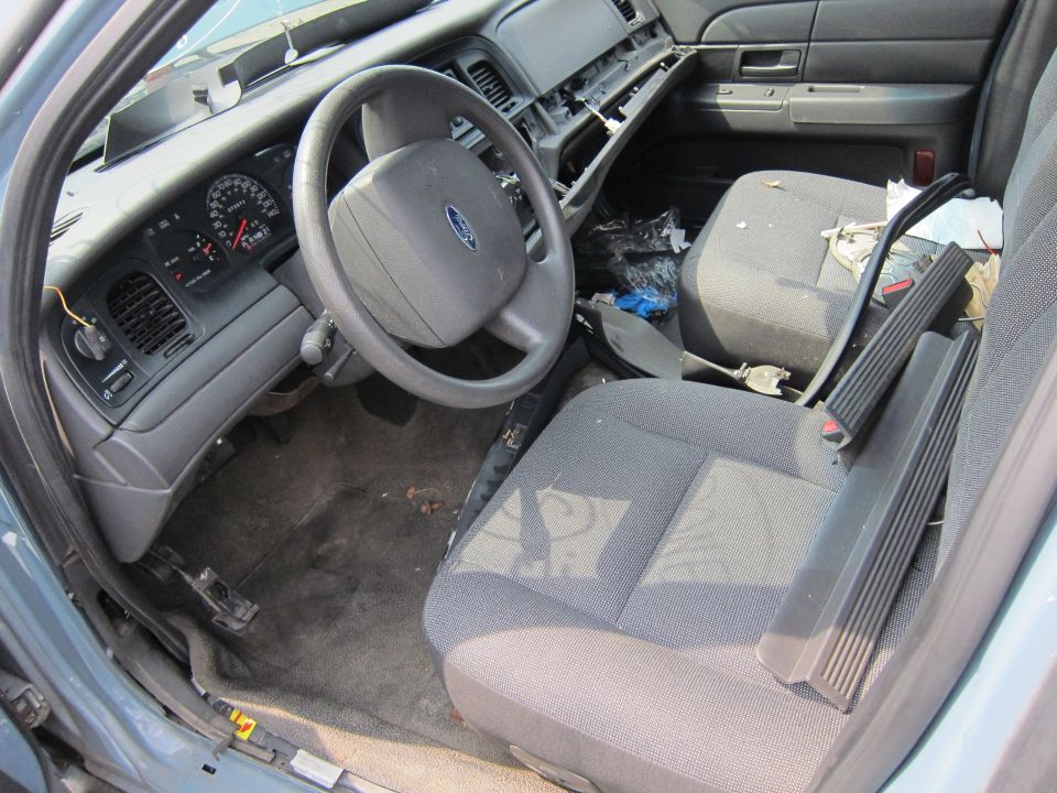 Interior of a blue 2001 Ford Crown Victoria showing the dashboard, steering wheel, and front seats. The interior is dirty and appears to be in disrepair