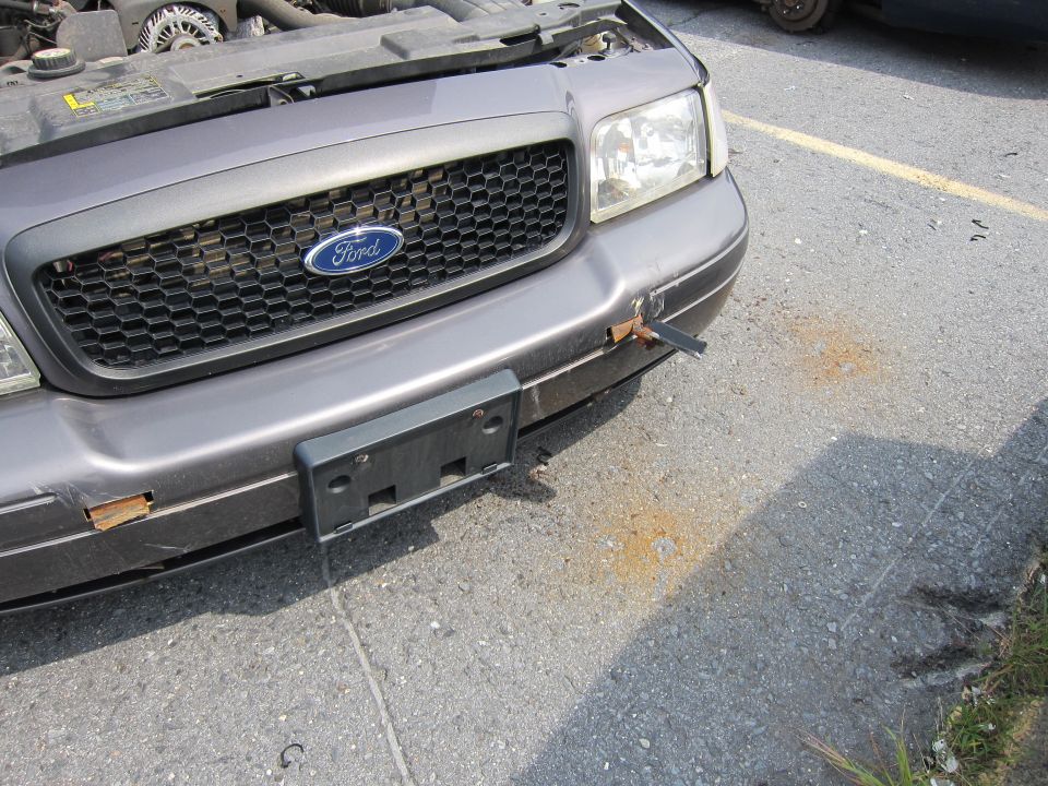 Gray 2001 Ford Crown Victoria front grille with Ford logo, damaged bumper, and open hood
