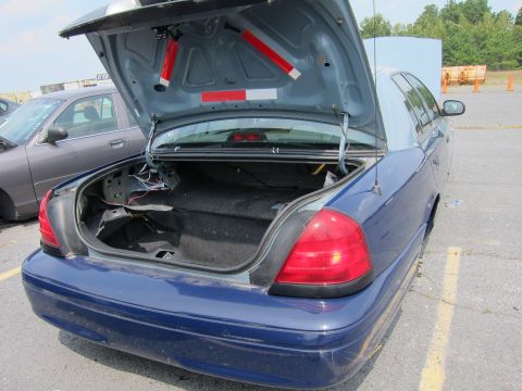 2001 Ford Crown Victoria - Rear view of a blue 2001 Ford Crown Victoria, trunk open, revealing interior components and wiring.