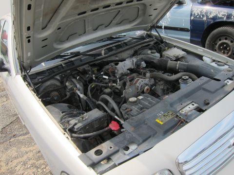 2001 Ford Crown Victoria - The engine compartment of a 2001 Ford Crown Victoria is shown with the hood open, and another vehicle is parked behind it.