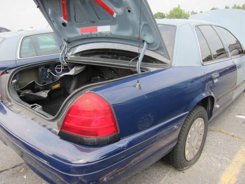 2001 Ford Crown Victoria - A blue 2001 Ford Crown Victoria is seen with its trunk open, parked next to another vehicle.