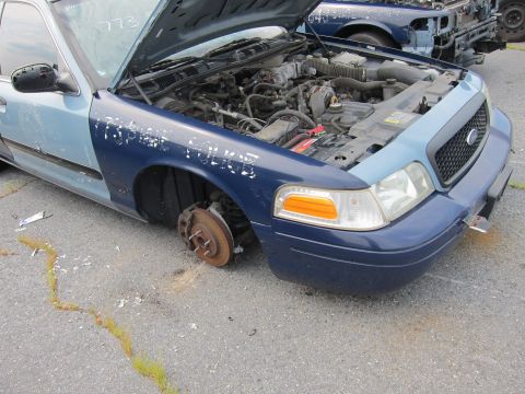 2001 Ford Crown Victoria - This 2001 Ford Crown Victoria is missing its front driver's side wheel and has its hood open.