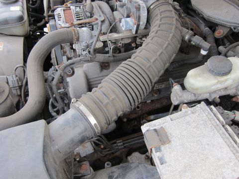 2001 Ford Crown Victoria - Close-up view of a dusty engine bay, showing various mechanical parts and hoses.