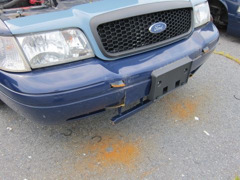 2001 Ford Crown Victoria - Front view of a damaged blue 2001 Ford Crown Victoria, showing rust on the bumper and grille.